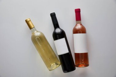 top view of bottles with white, red and rose wine on white background clipart