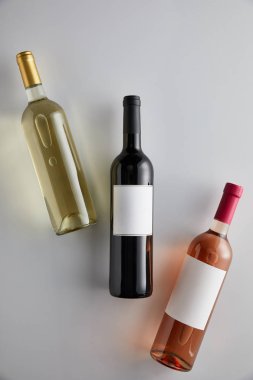 Beyaz arka planda beyaz, kırmızı ve gül şarabı olan şişelerin üst görüntüsü