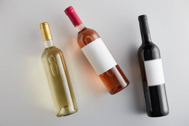 Beyaz zemin üzerinde beyaz, gül ve kırmızı şarap bulunan şişelerin üst görüntüsü