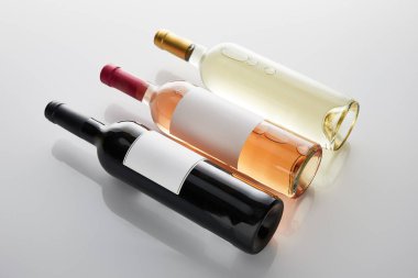 Beyaz arka planda beyaz, gül ve kırmızı şarap şişeleri