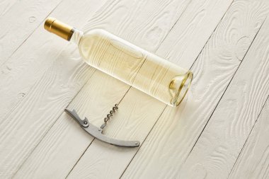 bottle with white wine near corkscrew on white wooden surface clipart