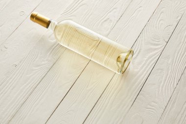 Beyaz ahşap yüzeyde beyaz şarap şişesi