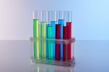 Mavi arka planda renkli sıvı bulunan cam test tüpleri