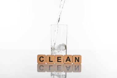 clear fresh water pouring in glass near cubes with clean lettering isolated on white clipart