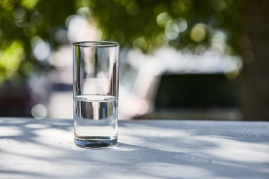 Güneşli bir günde şeffaf bardakta temiz su, ahşap masada.