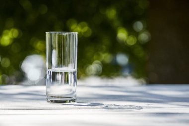 fresh clean water in transparent glass at sunny day outside on wooden table clipart