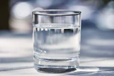Güneşli bir günde şeffaf bardakta temiz su.