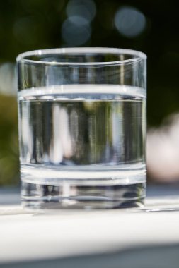 Güneşli bir günde şeffaf bardakta temiz su.