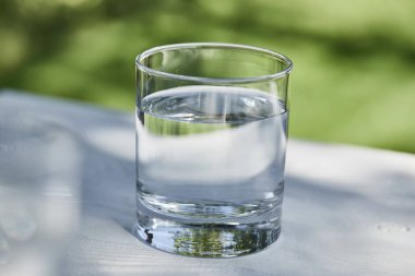 Güneşli bir günde şeffaf bardakta temiz su.
