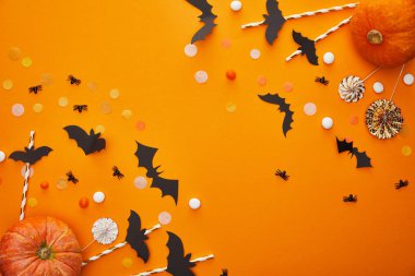 top view of pumpkin, bats and spiders with confetti on orange background, Halloween decoration clipart