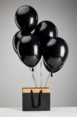 Gri, siyah cuma konseptine izole edilmiş kağıt alışveriş torbalı bir grup siyah balon.