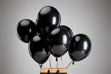 Gri, siyah cuma konseptine izole edilmiş kağıt alışveriş torbalı bir grup siyah balon.