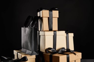 Kara Cuma konseptine izole edilmiş siyah kurdeleli ve alışveriş çantalı karton hediye kutuları.