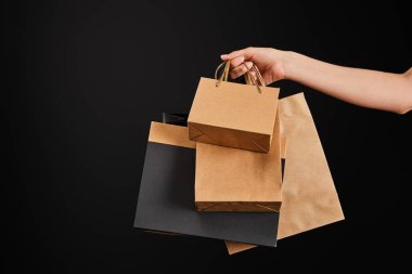 Siyah, siyah cuma konseptine izole edilmiş kağıt alışveriş torbaları taşıyan kadın görüntüsü