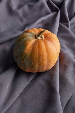 Gri kumaş üzerinde olgun bir balkabağı.