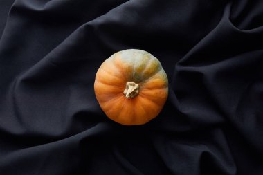 Olgun balkabağının siyah kumaş üzerindeki üst görüntüsü.