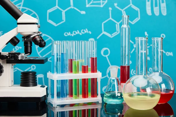 Mikroskop Reagenzgläser Und Kolben Mit Bunter Flüssigkeit Auf Blauem Hintergrund — Stockfoto