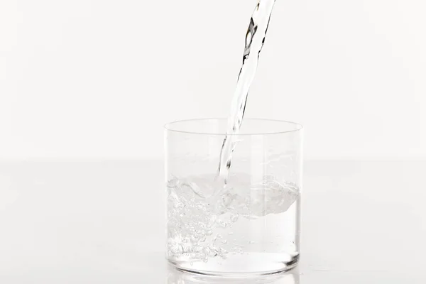 白で隔絶されたガラスに新鮮な水を注ぐと — ストック写真