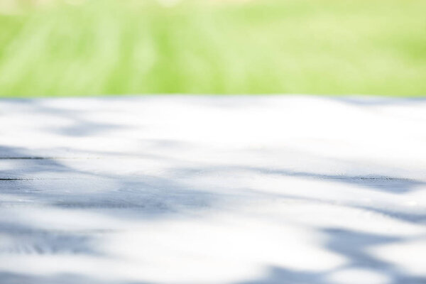 white wooden table with shadows in sunlight outdoors