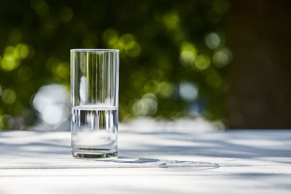 свежая чистая вода в прозрачном стекле в солнечный день снаружи на деревянном столе
