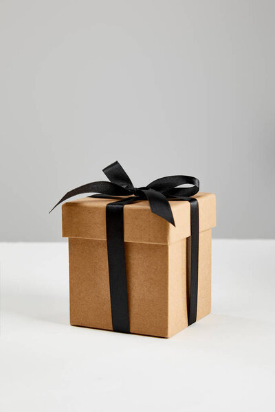 cardboard gift box with black ribbon isolated on grey, black Friday concept