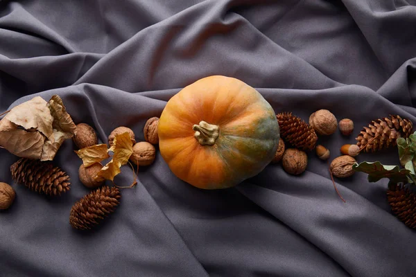 灰色の布に秋の装飾が施された熟した全体のカラフルなカボチャのトップビュー — ストック写真