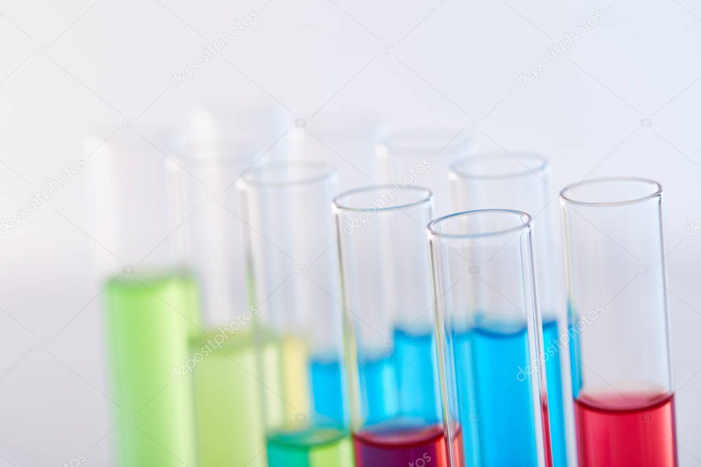 close up view of glass test tubes with colorful liquid isolated on white