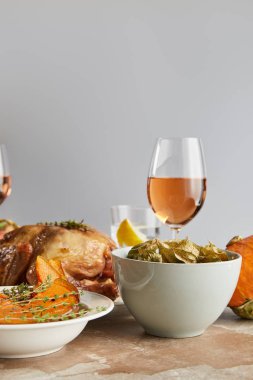baked physalis, sliced pumpkin and grilled turkey near glass with rose wine isolated on grey clipart