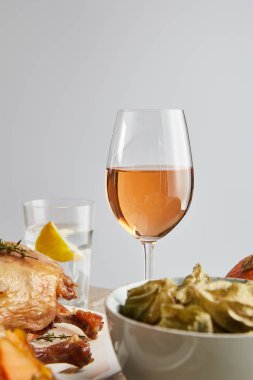 selective focus of glass with rose wine near grilled turkey and backed physalis isolated on grey clipart