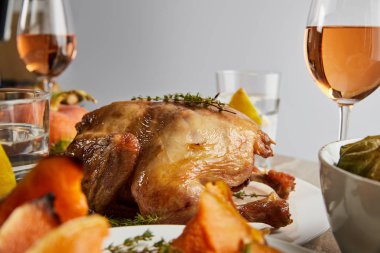 selective focus of whole grilled turkey near glasses with rose wine isolated on grey clipart
