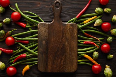 top view of chili peppers, cherry tomatoes, green peas, brussels sprouts and cutting board  clipart