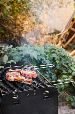 Mangal ızgarasında çiğ et ve dışarıda kömür parçaları. 