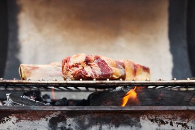 raw meat grilling on barbecue grid and coal pieces outside  clipart