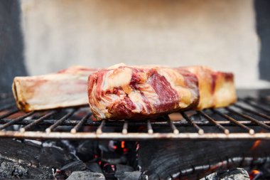 Mangal ızgarasında çiğ et ve dışarıda kömür parçaları. 