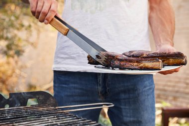 Tabağında et tutan cımbızlı adam manzarası 