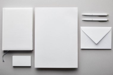 Kağıt, defter, kalem, kartvizit ve beyaz zarfın üst görünümü 