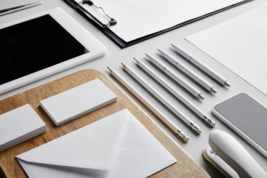 Tahtadaki kartvizit ve zarf, pano, zımba, kalem, kalem, kağıt, akıllı telefon ve dijital tablet 