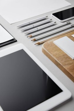 Tahta tahtadaki kartvizitler, kalemler, kalemler, kağıt, akıllı telefon ve dijital tablet 