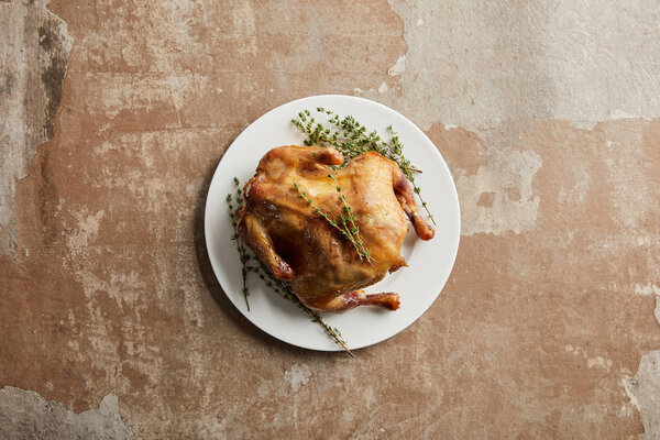 top view of whole grilled turkey with rosemary on stone textured surface