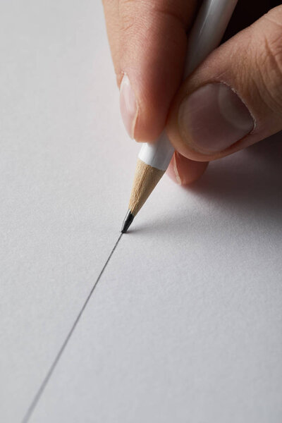 cropped view of man drawing line on paper with pencil 