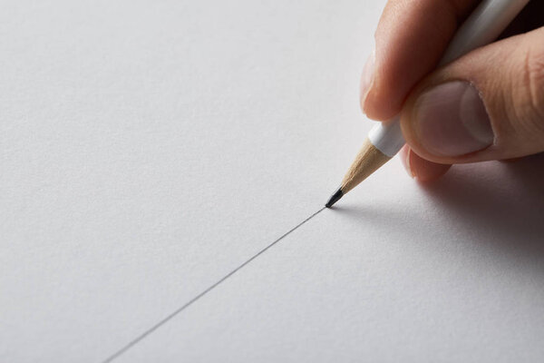 cropped view of man drawing line on paper with pencil 