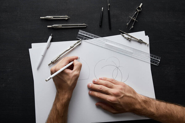 cropped view of architect drawing circle on white paper with pencil 