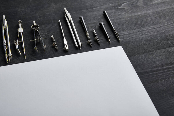 белая бумага с копировальным пространством и компасами на черном и деревянном столе
 