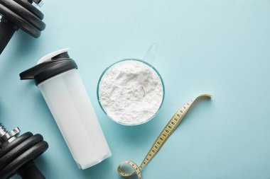 Spor şişesinin yanındaki dambılların üst görüntüsü ve mavi şeritteki ölçüm bandı. 