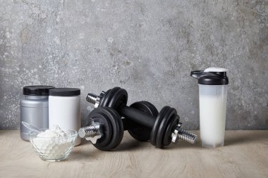 protein shake in sports bottle near jars near concrete wall  clipart