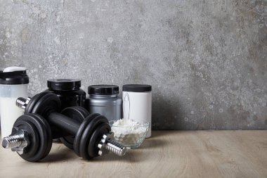 Spor şişesinde protein içeceği ve beton duvarın yanında protein tozu. 