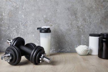 Spor sepetinde protein içeceği ve beton duvarın yanında protein tozu. 