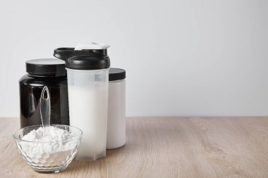 Gri kavanozların yanında protein içeceği bulunan spor şişesi.