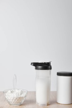 Kavanoz ve cam kasenin yanındaki spor şişesinde protein içeceği var.