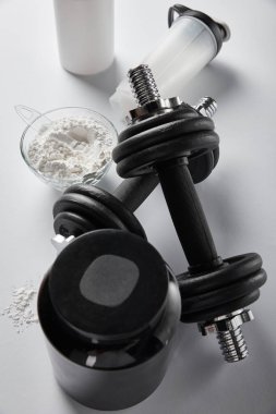 top view of sports bottle near bowl with protein powder and dumbbells on white  clipart
